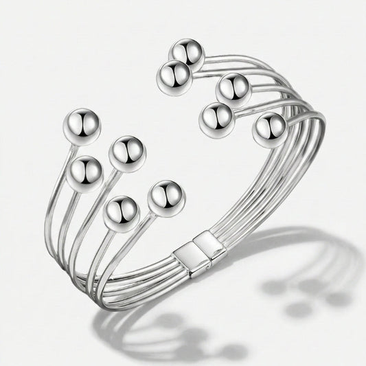 Damenarmband mit mehreren glatten Metallreihen und polierten Kugelenden, in Gold- oder Silberoptik am Handgelenk und in Detailansicht dargestellt